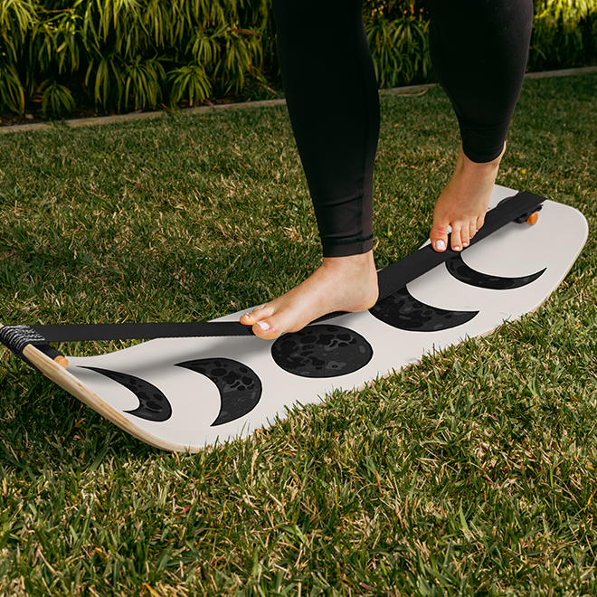 Women balancing on a moon slackboard outdoors on a lawn