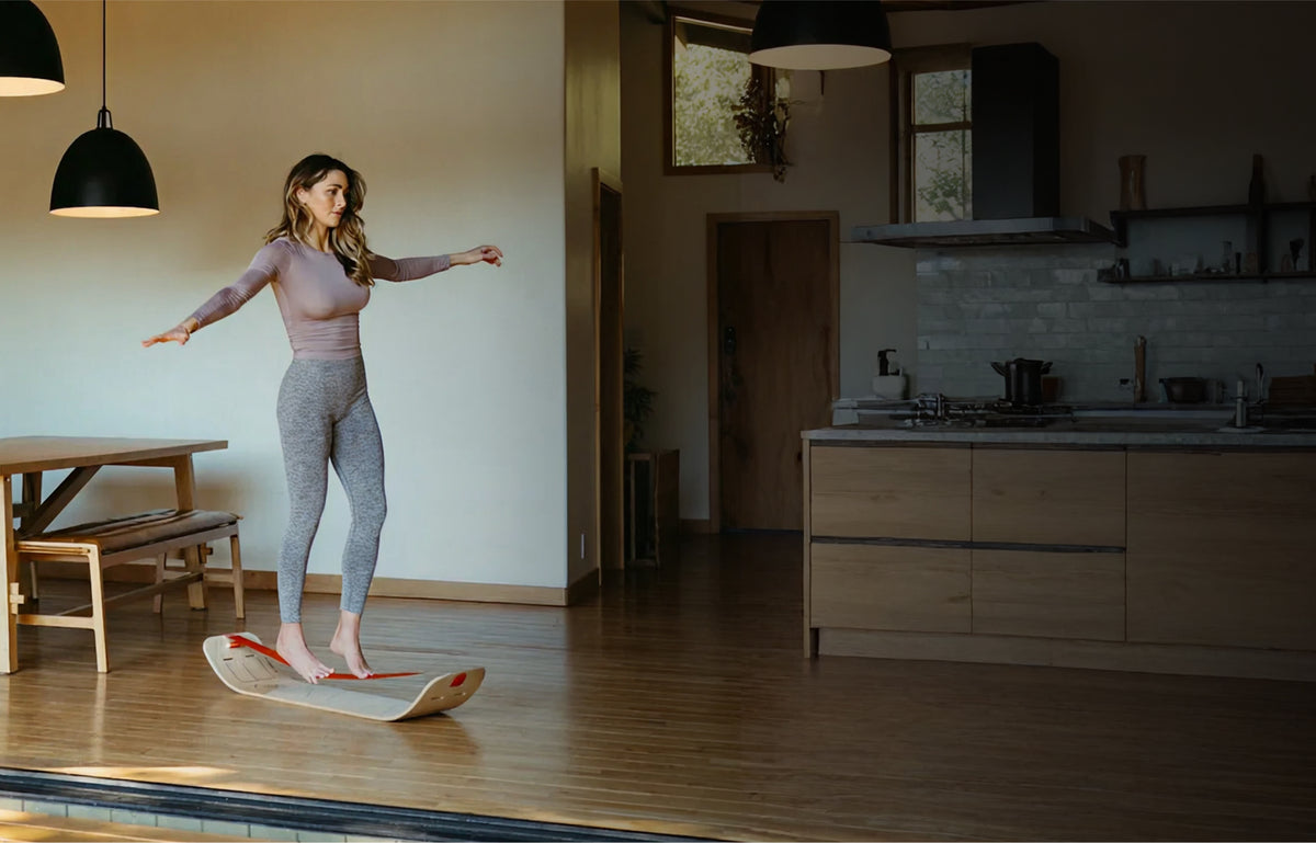 Woman balancing on a GIBBON SlackBoard at home