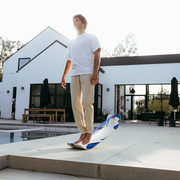 Person balancing on a Mountain SlackBoard in front of a modern house.
