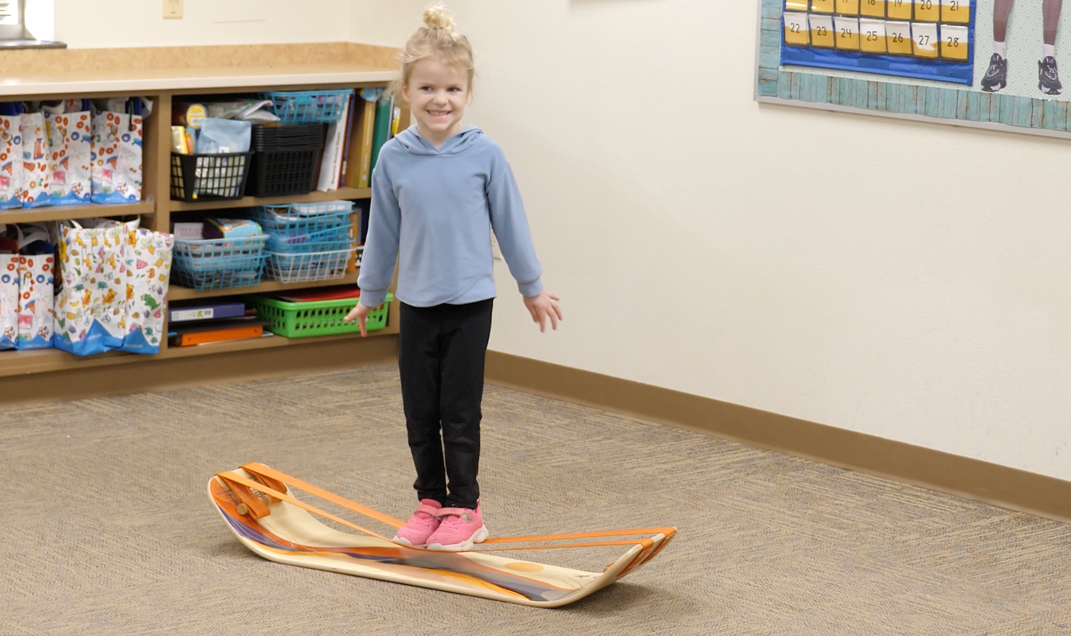 A child practicing balance on a GIBBON SlackBoard in a classroom